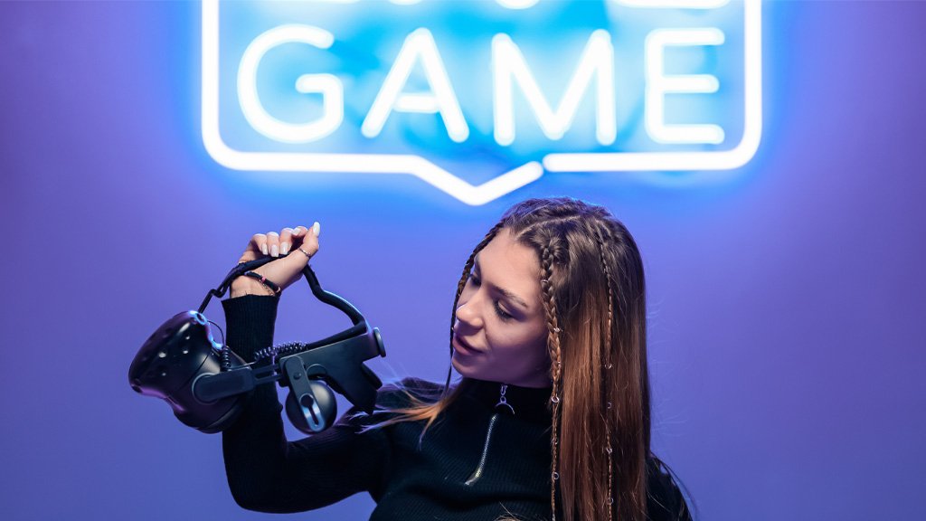 Woman holding a vr headset with game neon sign on wall