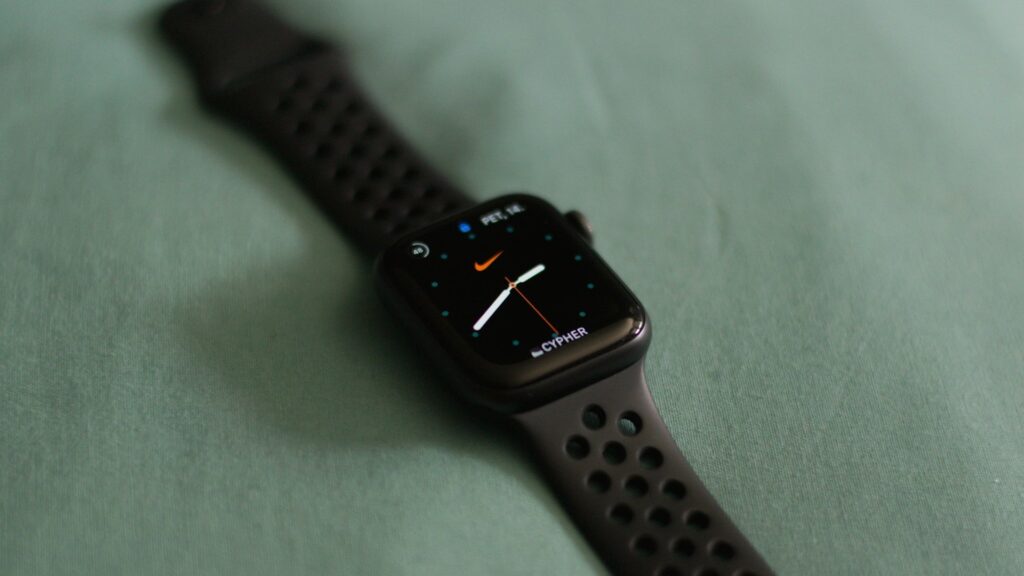 Apple Watch with a black perforated Nike sport band resting on a soft fabric surface