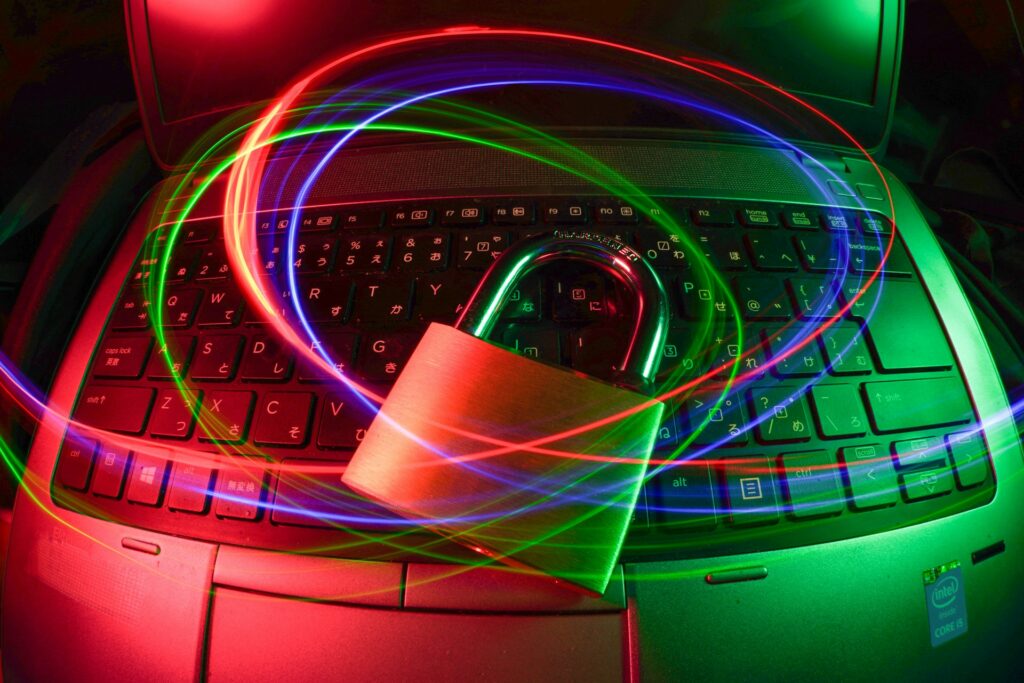 Gaming laptop with neon red and green lighting, RGB headphones resting on keyboard in dark studio setting.