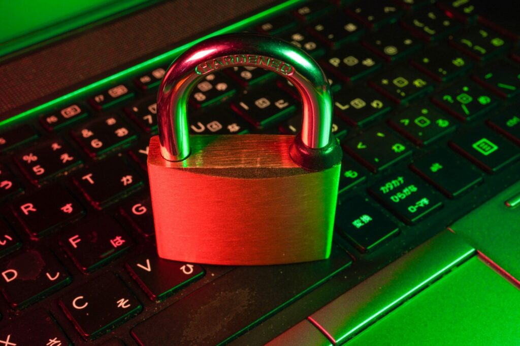 A neon-lit padlock glowing red and green sits on a gaming keyboard illuminated by RGB lighting.